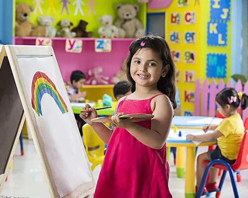 A girl painting a rainbow at an easel