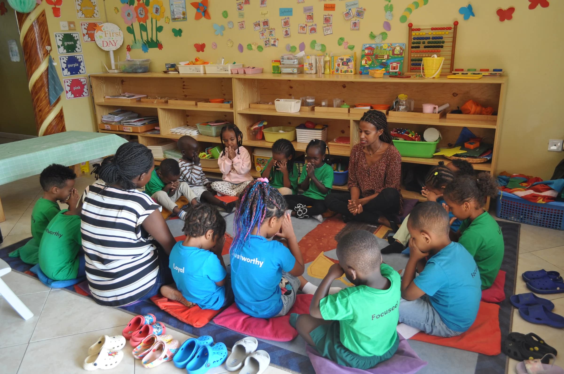 Children and teachers gathered in a circle with books and learning materials at Eco-Bloom
