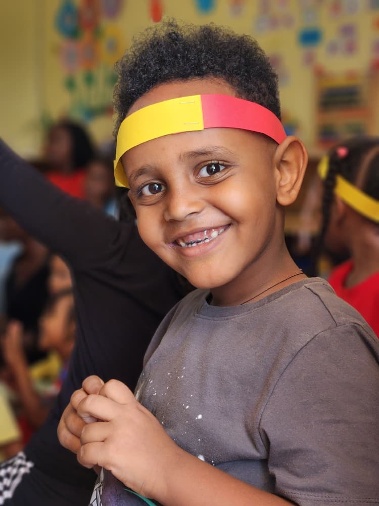 A smiling Eco-Bloom pupil wearing a Uganda-coloured headband