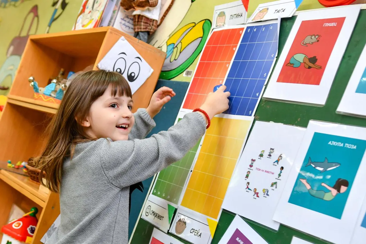 A girl placing a card on a classroom wall chart